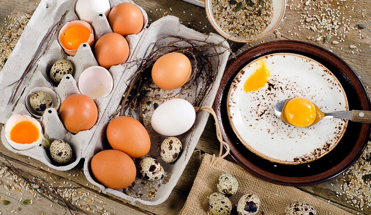 Miska z rozbitymi surowymi jajami obok opakowania świeżych jaj
