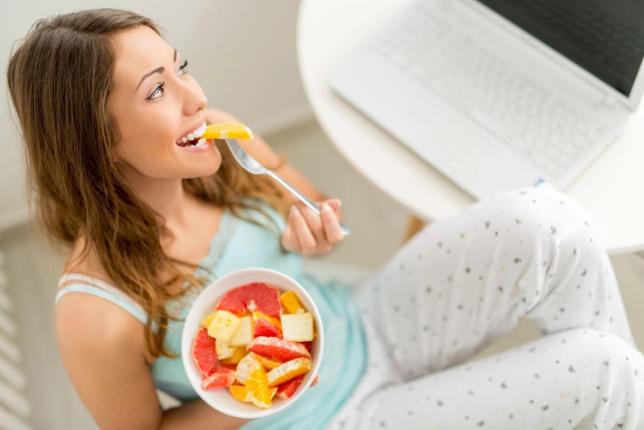 Uśmiechnięta kobieta jedząca sałatkę owocową